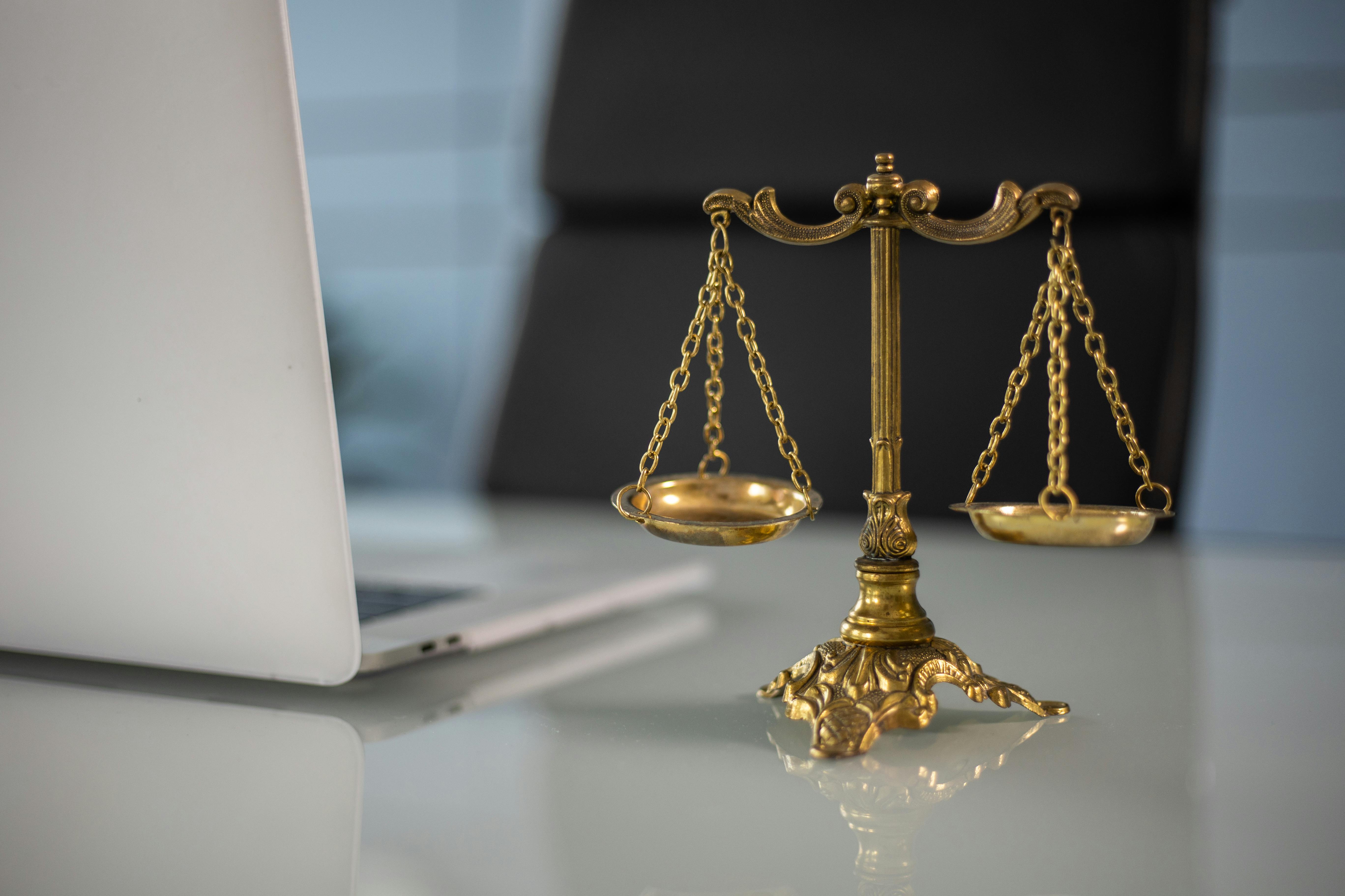 Golden scales beside a laptop on a desk